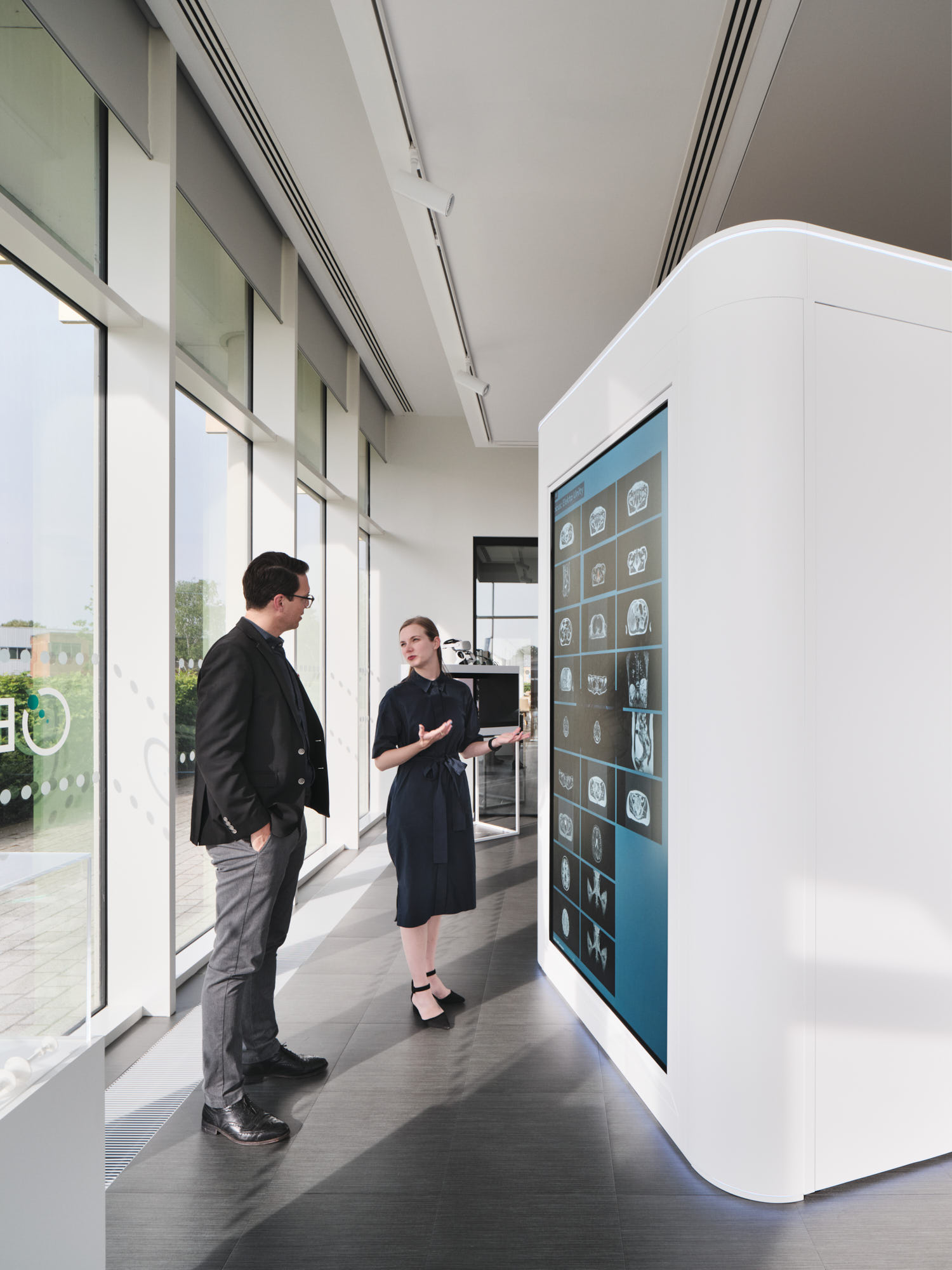 Two people standing in front of an interactive touch screen application.