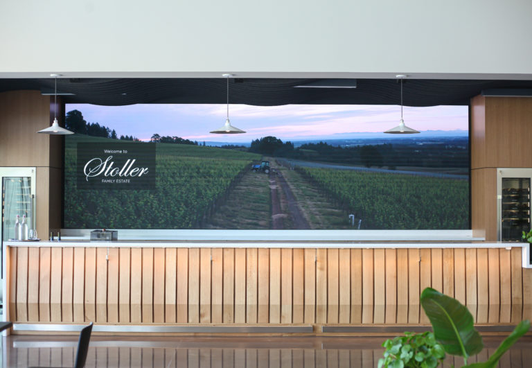 A photo of the Stoller Barback app, a large LED screen behind a winery bar that teaches people about the winery.